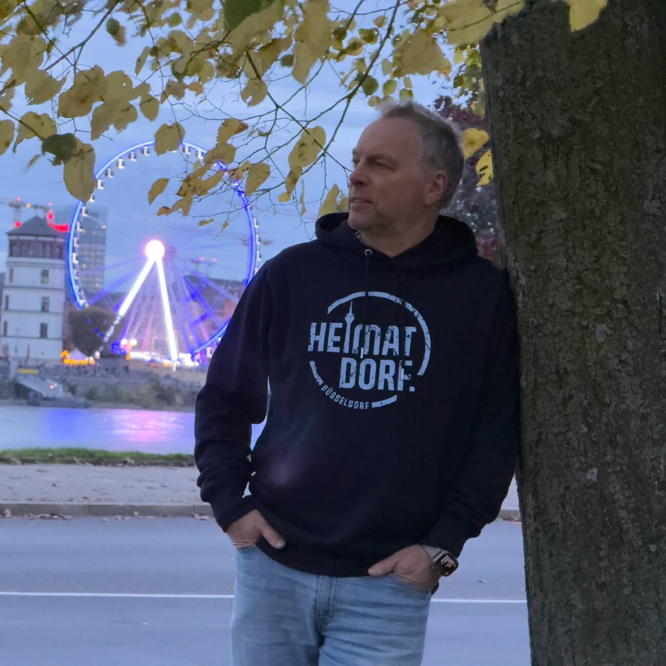 Ein Mann mit HEIMATDORF Hoodie an den Rheinwiesen